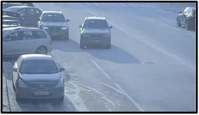 LPR camera view of a multi-lane road with a sedan and other vehicles stopped along the roadway