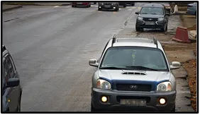 LPR camera front-facing view of an SUV parked among other vehicles along a street