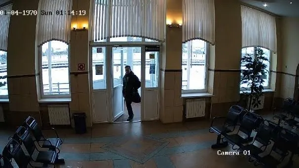 Bad camera placement example: a person entering a large hall through a distant doorway, backlit by daylight and too small and dim to recognize